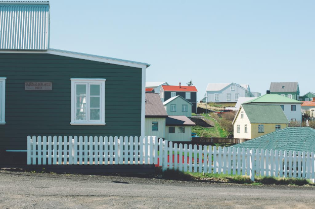 Eine Reihe von Häusern mit einem klaren Himmel darüber und Grasland dazwischen.