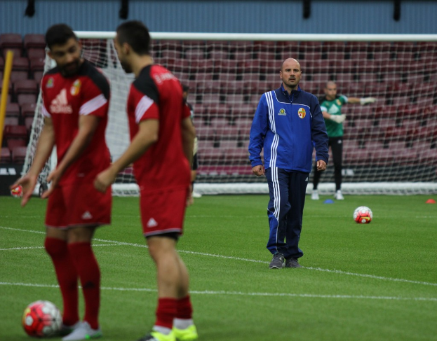 Ein Fußballfeld mit Spielern darauf, zwei Bälle sind sichtbar und das Stadion ist leer im Hintergrund.