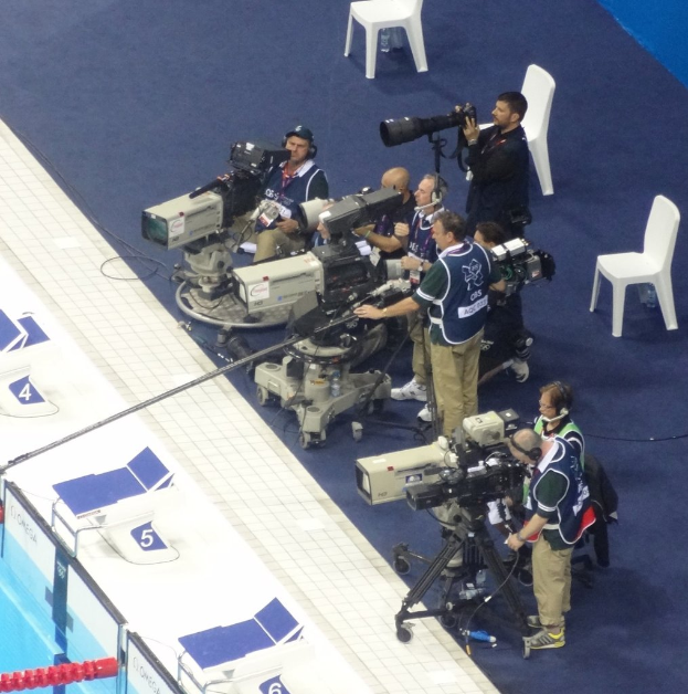 Eine Gruppe von Menschen mit Kameras, im Hintergrund sind mehrere Stühle zu sehen.