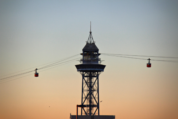 Mehrere Kabelbahnen an Seilen mit einem Turm im Hintergrund.