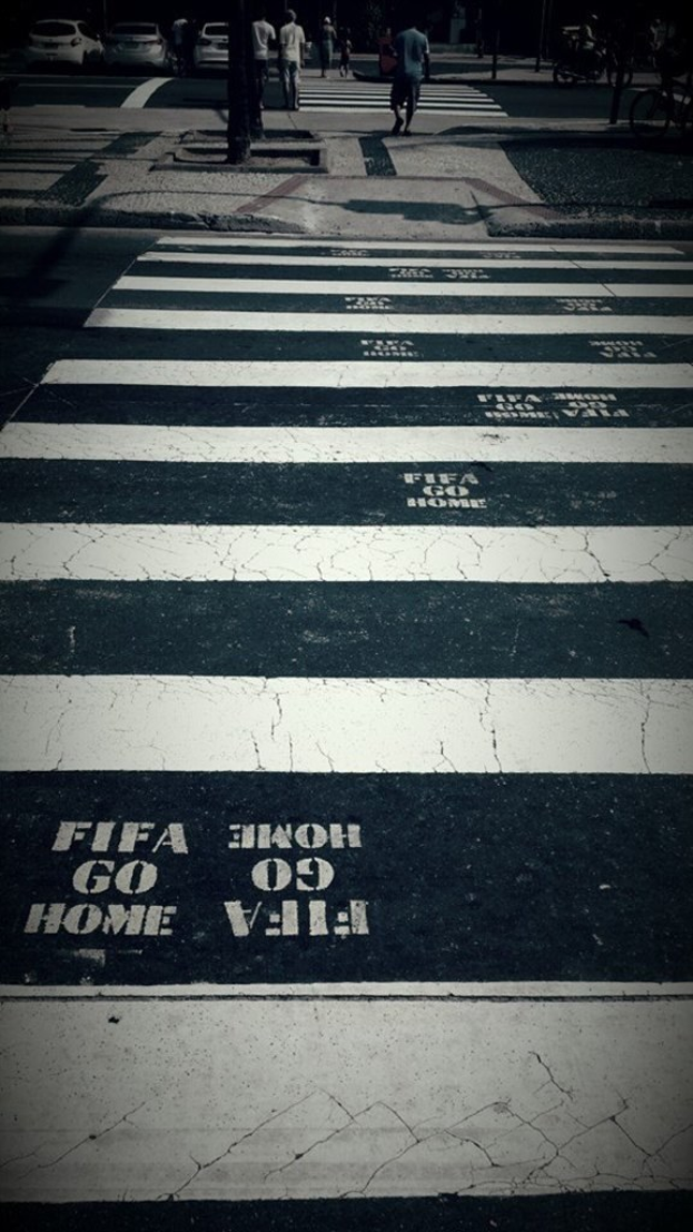 Menschen überqueren eine Fußgängerfurt, während Autos in der oberen linken Ecke zu sehen sind.