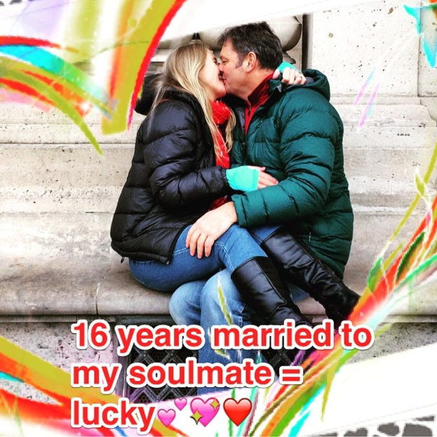 Eine Frau und ein Mann küssen sich, beide tragen Jacken, mit sichtbarem Text auf dem Bild.