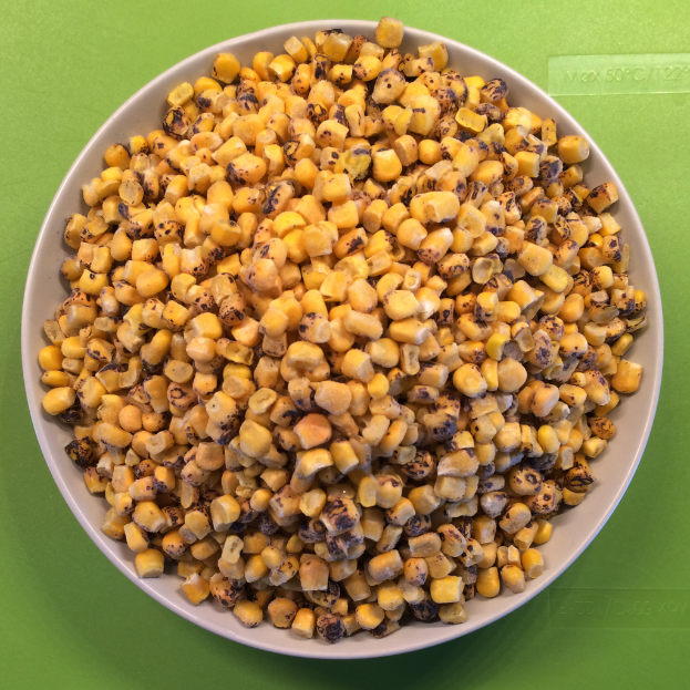 Ein weißer Schüssel mit Maiskörnern steht vor einem grünen Hintergrund mit Text unten.