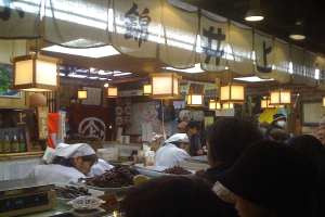 Restaurantmitarbeiter bereiten Artikel hinter einer Theke mit Kunden davor vor, Sauceflaschen und Menüs im Hintergrund sichtbar