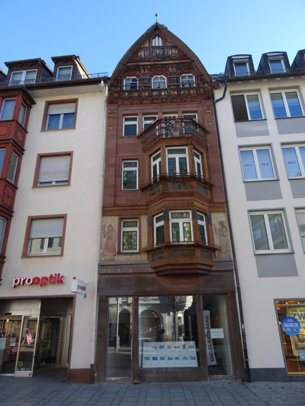 Ein Geschäftsgebäude mit zahlreichen Fenstern an der Seite, das sich an einer Straße in Heidelberg, Deutschland, unter einem klaren blauen Himmel befindet.