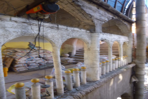 Altes Gebäude mit Bogengängen, Säulen, Treppen, Geländern, verstreuten Renovierungswerkzeugen und -materialien, mit einer Maschine und Drähten oben und Gegenständen auf der rechten Seite.