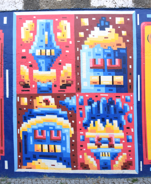 Ein buntes Wandgemälde an einem Gebäude in Berlin, Deutschland, das verschiedene Formen und leuchtende Farben zeigt.