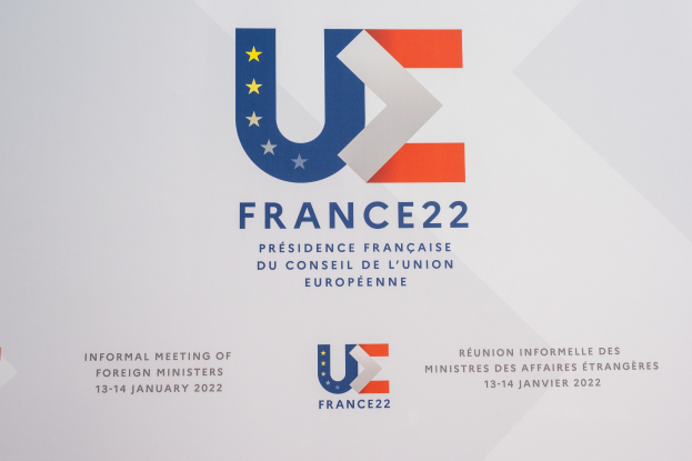 Plakat mit der Aufschrift "Frankreich 22 - Informelles Treffen der Außenminister" und dem Logo der Europäischen Union, das einen blauen Kreis, einen weißen Rahmen, einen weißen Stern und einen weißen Rand zeigt.