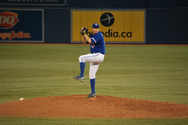 Ein Spieler steht auf dem Boden und hält einen Ball, im Hintergrund ist eine große Fahne mit Text und Bildern zu sehen.