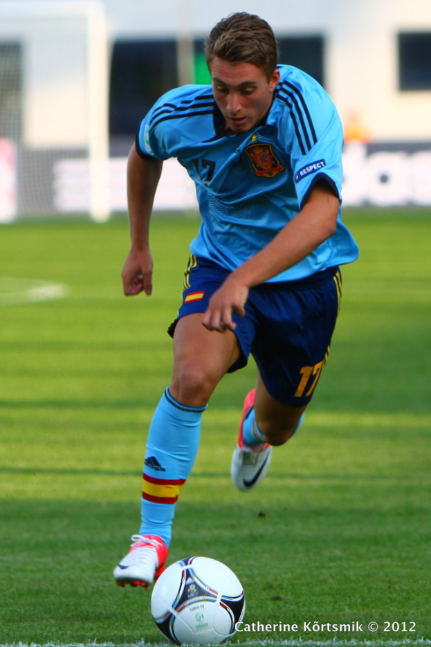 Ein Mann in einem blauen T-Shirt spielt Fussball auf einem Feld.