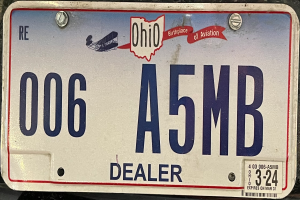 Ein Kennzeichen an der Rückseite eines Autos mit Text und Zahlen.