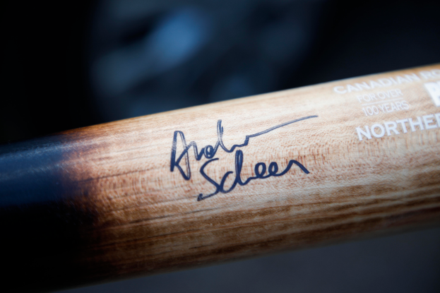 Ein Close-up eines hölzernen Hockey-Schlägers mit einer Signatur und Text, wahrscheinlich der Name des Spielers.