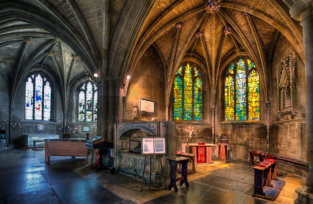 Ein Raum mit Bänken, Tischen, einer Tafel, Kerzen, einem Kamin und Lampen, mit Fenstern auf beiden Seiten, bearbeitet.
