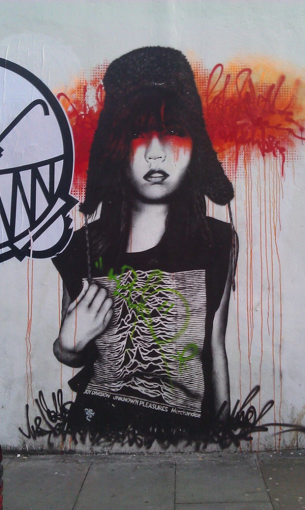 Graffiti auf einer weißen Wand mit Gehweg unten.