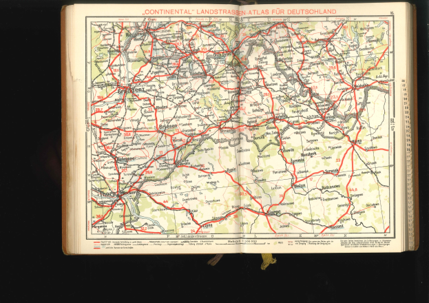 Offenes Buch mit detaillierter Karte von Deutschlands Straßen und Autobahnen auf schwarzem Hintergrund.