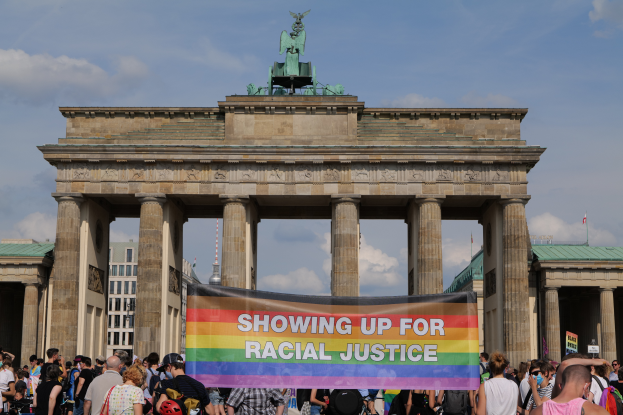 Eine Gruppe von Menschen steht vor dem Brandenburger Tor in Berlin, Deutschland, und hält eine Tafel mit der Aufschrift "Rassengerechtigkeit."