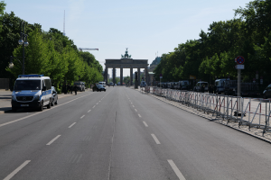 Ein Polizeiwagen steht am Straßenrand vor dem Reichstagsgebäude in Berlin, Deutschland, mit Barrieren, Schildern, Bäumen, Laternenmasten und einer bewölkten Himmelovisibilität.