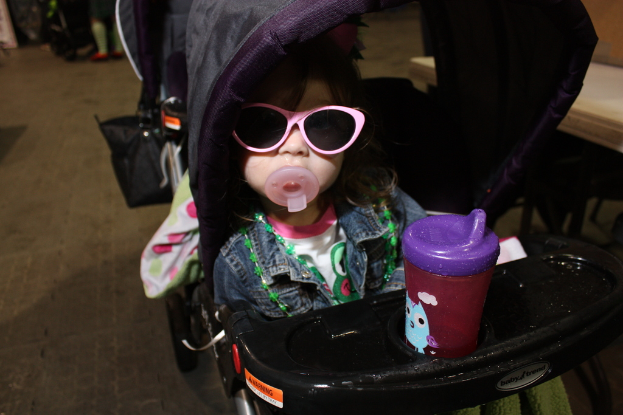 Kind in einem Laufwagen auf der Straße sitzend.