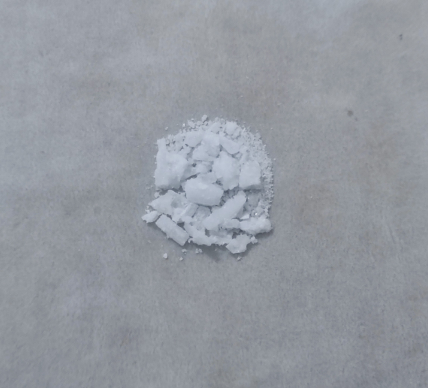 Ein Haufen weißes Salz auf einem Zementboden, mittig im Bild mit weißem Hintergrund.