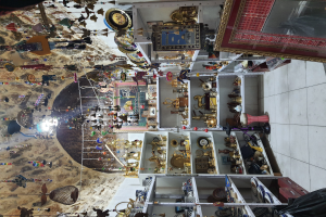 Ein überfülltes Souvenirgeschäft mit verschiedenen Artikeln, darunter Gegenstände in Schränken, von der Decke hängende Dekorationen und ein Teppich auf dem Boden.