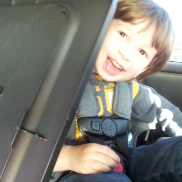 Ein Junge sitzt in einem Auto und lächelt.