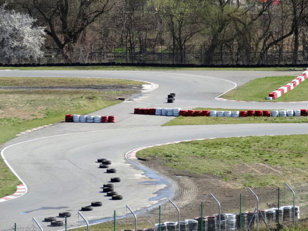 Rennstrecke voller Reifen, umgeben von Gras und Maschendrahtzaun, mit Bäumen im Hintergrund.