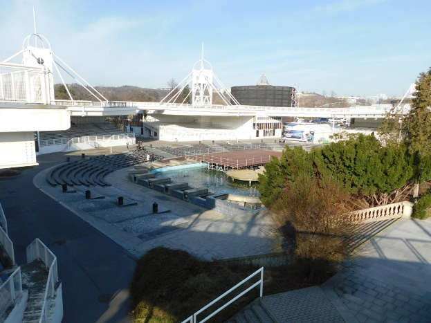 Luftaufnahme des Olympischen Stadions mit umgebender Vegetation, städtischen Elementen und wolkenbedecktem Himmel.