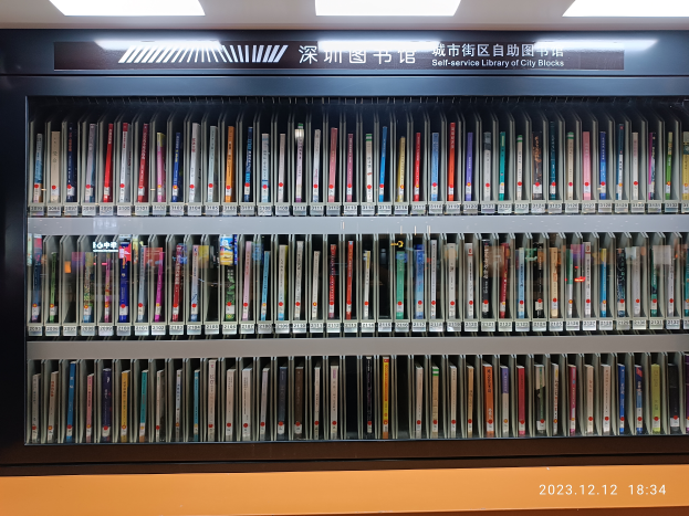 Eine gut beleuchtete Bibliothek mit zahlreichen Büchern auf Regalen, einem Textschild und einem Wasserzeichen unten, das wie eine Selbstbedienungsbibliothek von Stadtblöcken aussieht.