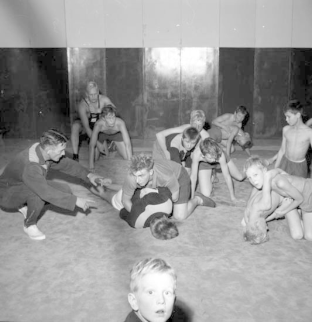 Schwarz-weißes Foto von jungen Jungs, die in einem Fitnessstudio ringen, mit einer Wand im Hintergrund.