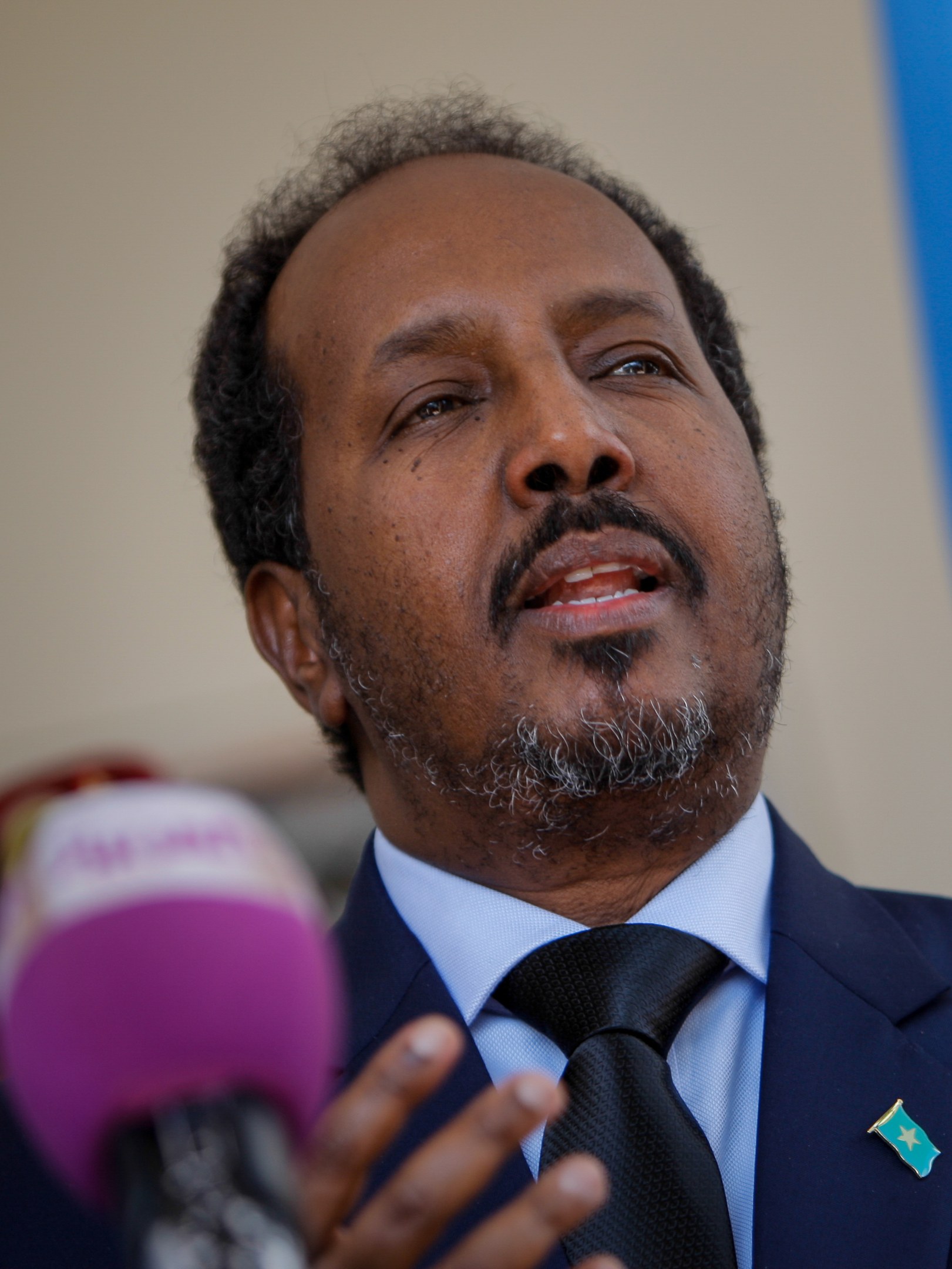 Ein Mann im Anzug und mit Krawatte spricht in ein Mikrofon, wahrscheinlich zu einem Publikum als Politologe.