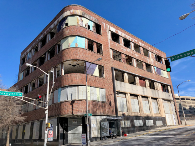 Altes Backsteingebäude an einer Straßenecke, als ehemaliger Hauptsitz der University of Illinois at Chicago markiert, mit Straßeninfrastruktur und Fahrzeugen im Hintergrund.