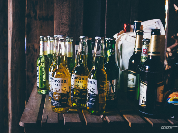 Zwei verschiedene Flaschenarten mit einer Tasche im Hintergrund, die weitere Flaschen enthält.