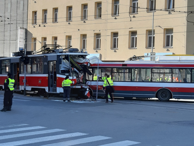 Rote und weiße Straßenbahn krachte auf der Seite der Straße mit Menschen in der Nähe und einem Gebäude im Hintergrund.