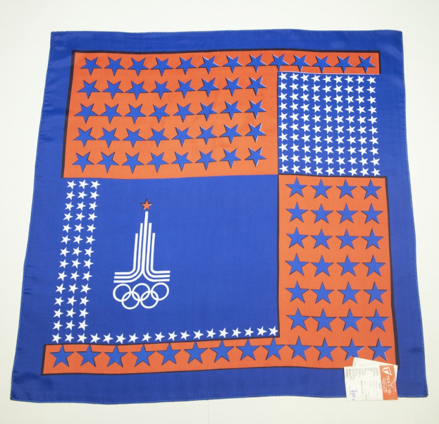 Ein blaues und oranges Bandana mit dem Olympischen Logo, vor einem weißen Hintergrund.