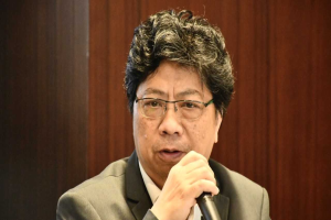 Ein Mann im Anzug in einer hitzigen Diskussion hält ein Mikrofon gegen eine hölzerne Wand als Hintergrund, Bezug nehmend auf die Suspendierung der Philippinen vor Gericht wegen COVID-19-Beteiligung.