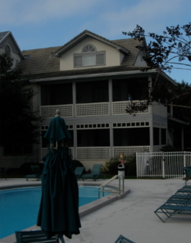 Ein Schwimmbad auf der linken Seite, ein Gebäude in der Mitte und der Himmel oben.