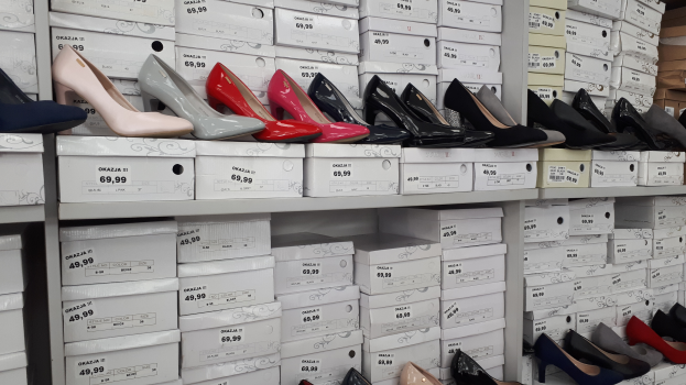 Ein Regal voller verschiedener Schuharten in Kartons, jeweils mit einem Preisschild, und Kartonagen auf der rechten Seite.