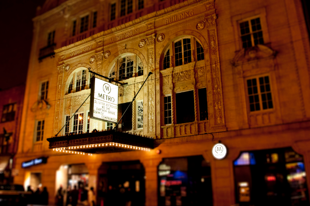 Ein gelbes Gebäude mit Geschäften im Erdgeschoss, eines davon hat ein weißes Schild mit dem Wort 'Metro' darauf.
