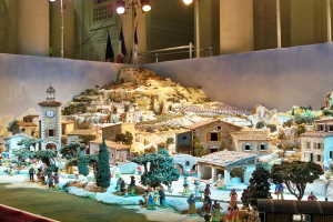 Ein detailliertes Modell einer Krippe, das in einem Museum ausgestellt wird und Figuren, Strukturen und beleuchtete Elemente enthält.