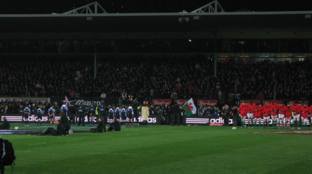 Eiserner Gitter und Lautsprecher oben auf dem Bild, mit einer Menge, Werbung, Fahne und Boden unten.
