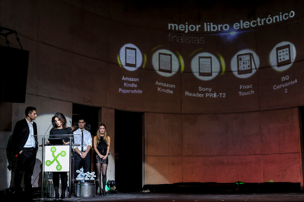 Vier Personen stehen links, wobei eine Frau ein Seminar hält; im Hintergrund sind Bilder von Gadgets zusammen mit ihren Namen angezeigt.