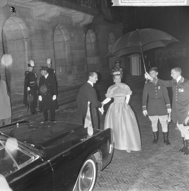 Schwarzes und weißes Foto von Queen Elizabeth II. und Prinz Philip, Duke of Edinburgh, bei der Ankunft auf Buckingham Palace in formeller Kleidung, wobei die Queen einen Blumenstrauß und der Duke einen Schirm hält.
